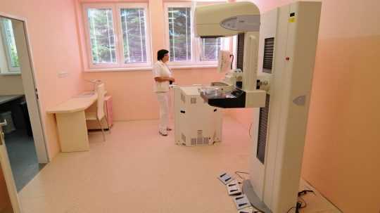 Zdravotná sestra sleduje monitor obsluhovacieho panelu mamografu.