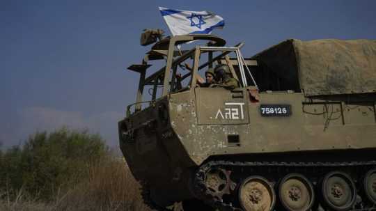 Izraelskí vojaci mávajú národnou vlajkou z tanku, ktorý smeruje k hraniciam pásma Gazy.