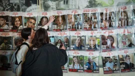 Ľudia pozerajú na plagáty s izraelskými zajatcami držanými v Gaze.