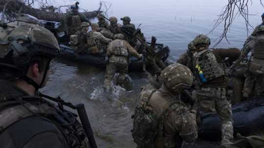 Ukrajinskí vojaci nastupujú do člna na frontovej línii pri Chersone.