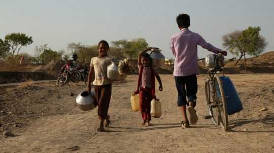 Indické deti idú s nádobami po vodu.
