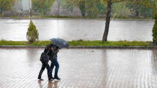 Na snímke žena a muž pod dáždnikom v daždi na ulici.