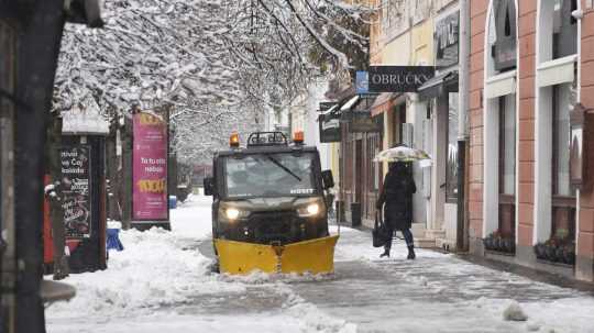 Odhrabávanie snehu z chodníka počas ranného sneženia v centre Košíc.