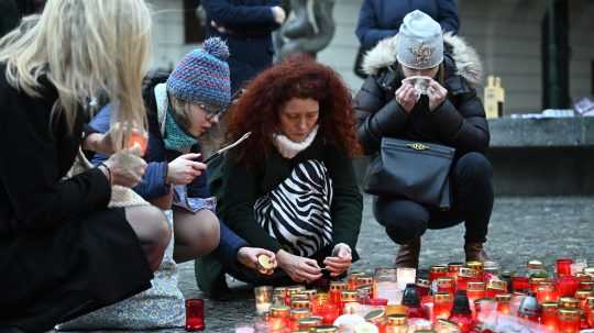 Ľudia zapaľujú sviečky pred budovou Filozofickej fakulty Univerzity Karlovej (FF UK) pre obete masovej streľby.