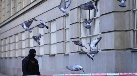 Policajt hliadkuje pred budovou Filozofickej fakulty Univerzity Karlovej (FF UK) po streľbe v centre Prahy