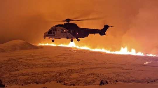 Na snímke vrtuľník letiaci v blízkosti magmy tečúcej na kopci neďaleko Grindavíku.