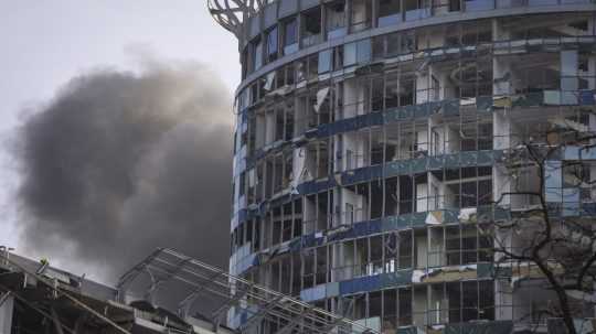 Dym stúpa za budovou poškodenou pri ruskom raketovom útoku v Kyjeve v piatok 29. decembra 2023.