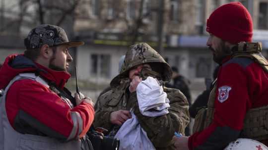 Zranená obyvateľka sa rozpráva so zdravotníkmi po ruskom raketovom útoku v Kyjeve.