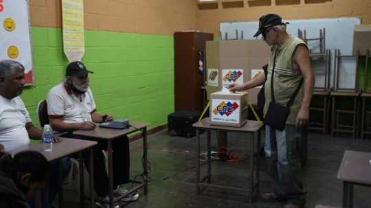 Muž vhadzuje elektronický hlasovací lístok do urny počas referenda o budúcnosti územia Guyany.