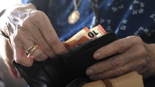 Na snímke senior drží v rukách peňaženku s peniazmi.