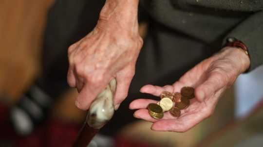 Seniorka drží v ruke euromince.