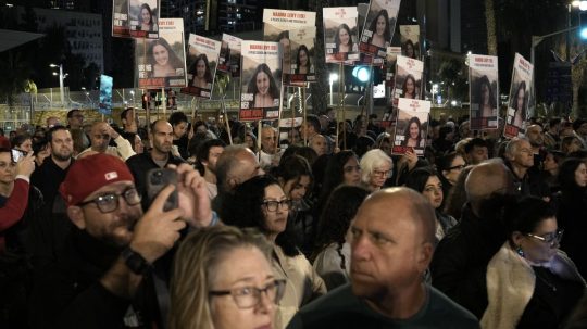 Ľudia držia transparenty s fotografiami rukojemníkov počas demonštrácie v izraelskom Tel Avive.