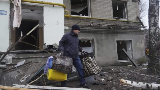 Muž sa evakuuje z obytného domu poškodeného ruským raketovým útokom v Charkove začiatkom januára.