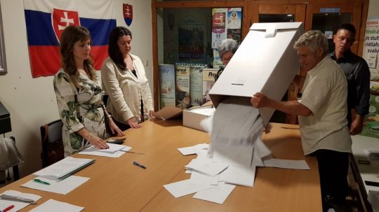 Člen okrskovej komisie vysýpa hlasovacie lístky z volebnej schránky.