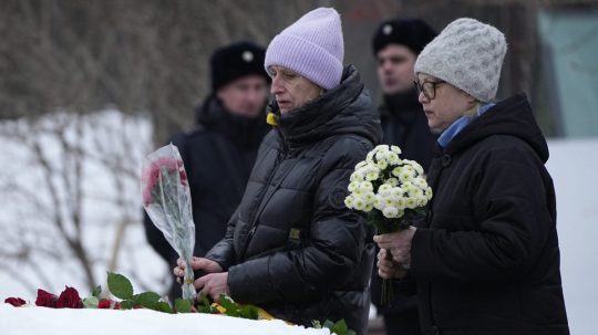 Ženy kladú kvety k pamätníku, veľkému balvanu zo Sloveckých ostrovov, kde bol zriadený prvý gulag pre politických väzňov v Moskve 24. februára 2024 na pamiatku zosnulého ruského opozičného lídra Alexeja Navaľného.