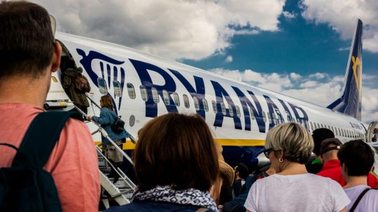 Ľudia v rade na letisku sa chystajú nastúpiť do lietadla spoločnosti Ryanair.