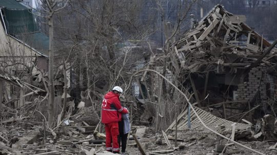 Zdravotnícky pracovník utešuje ženu na mieste ruského leteckého útoku v Záporoží na Ukrajine.