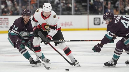 Tim Stutzle (18) z Ottawy Senators sa pohybuje s pukom pod tlakom Glenna Gawdina (42) a Pavla Regendu (40) z Anaheimu Ducks.