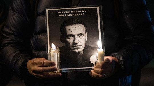 Muž drží portrét Alexeja Navaľného a horiace sviečky.