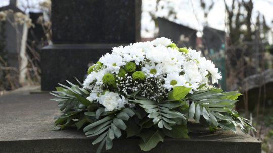 Pohrebný veniec z kvetov na náhrobku na cintoríne.