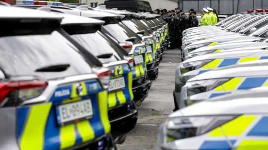 Policajti stoja pri nových autách.