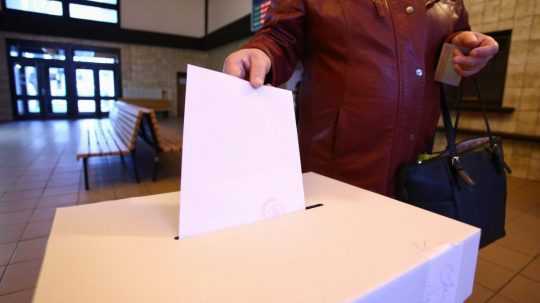 Žena vhadzuje obálku s hlasovacím lístkom do volebnej schránky.