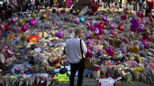 Muž stojí pri kvetoch za obete bombového útoku na Námestí svätej Anny v centre Manchestru, 26. mája 2017.