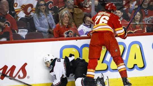 Útočník Arizony Coyotes Dylan Guenther (11) a útočník Calgary Flames Martin Pospíšil (76) počas zápasu v NHL.