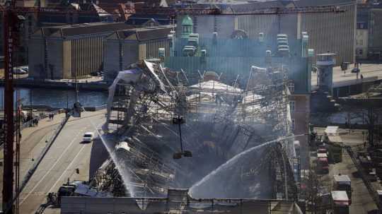 Hasiči zasahujú po utorňajšom požiari historickej budovy burzy v centre dánskej metropoly Kodaň.