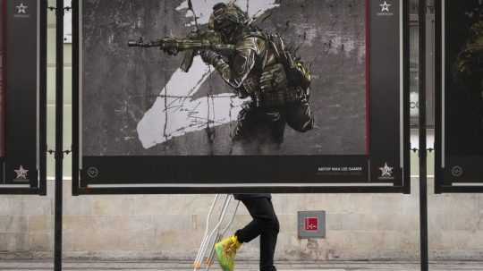 Petrohrad: Muž prechádza okolo pouličnej výstavy vojenských plagátov s názvom "Prinášame mier".
