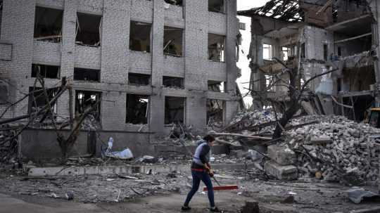 Miestny obyvateľ odstraňuje trosky pri budove poškodenej pri ruskom nálete v meste Orichiv v Záporožskej oblasti-