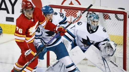 Útočník Calgary Flames Martin Pospíšil pred bránkou zvádza súboj s Calenom Addisonom zo San Jose Sharks.