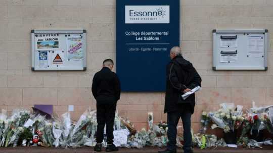 Miestni obyvatelia sa pozerajú na kvety položené pred vchodom do strednej školy Les Sablons v meste Viry-Chatillon 7. apríla 2024 po smrti tínedžera.