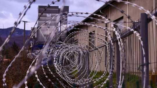 Na ilustračnej snímke budova väzenia obohnaná ostnatým drôtom.