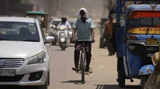 Muž sa pri jazde na bicykli chráni pred horúčavou.