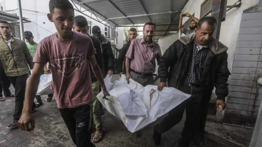 Ľudia odnášajú obete izraelského útoku v Rafahu.