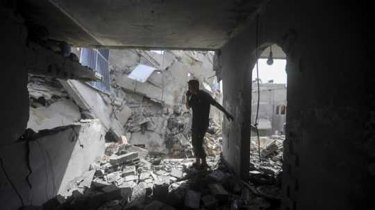 Palestínčania sa pozerajú na ruiny po izraelskom útoku.