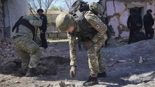 Policajt prezerá úlomky bomby po ruskom leteckom útoku na Charkov.