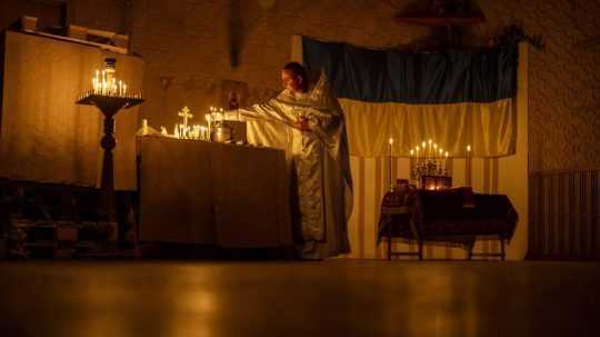 Kňaz zapaľuje sviečky počas pravoslávnej veľkonočnej bohoslužby v Doneckej oblasti na Ukrajine.