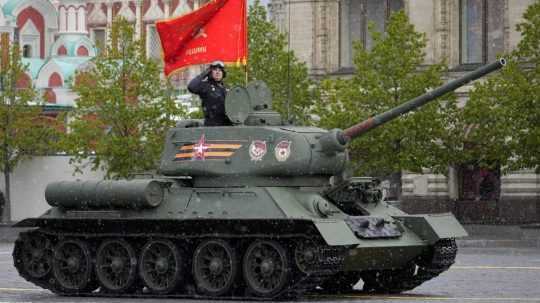 Legendárny sovietsky tank T-34 s červenou vlajkou na vrchole na Červenom námestí v Moskve počas vojenskej prehliadky.