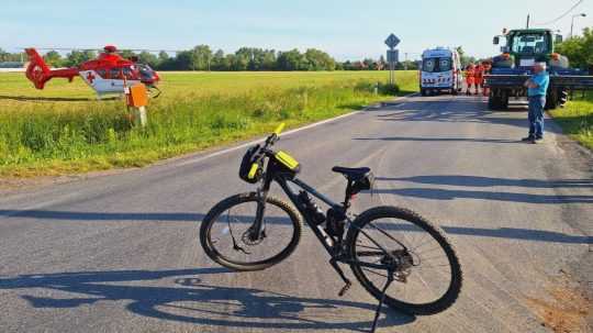 Na snímke bicykel odstavený na ceste, v pozadí záchranársky vrtuľník a vozidlá záchrannej služby.