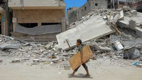 chlapec prechádza okolo trosiek budov v Rafahu