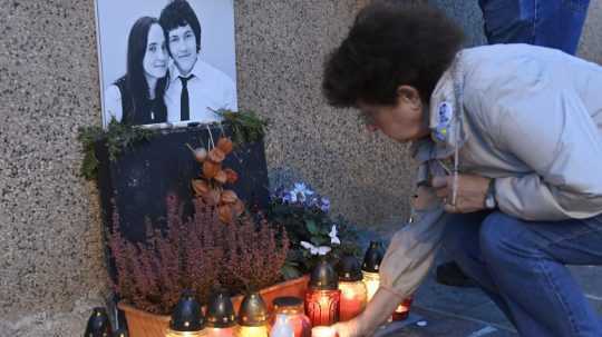 Žena zapaľuje sviečku pri fotografii Jána Kuciaka a Martiny Kušnírovej.