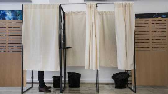 Volič upravuje hlasovací lístok vo volebnej miestnosti.