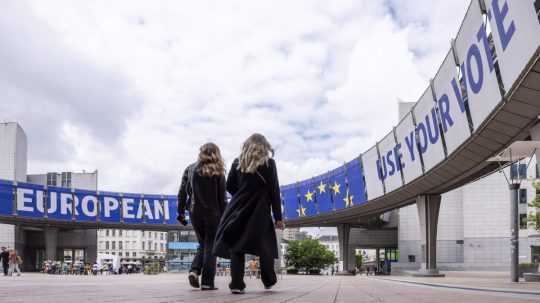 Ľudia kráčajú pred Európskym parlamentom v Bruseli.