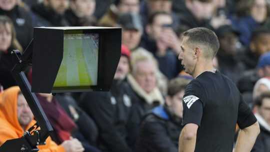 Rozhodca David Coote kontroluje obrazovku VAR počas futbalového zápasu.