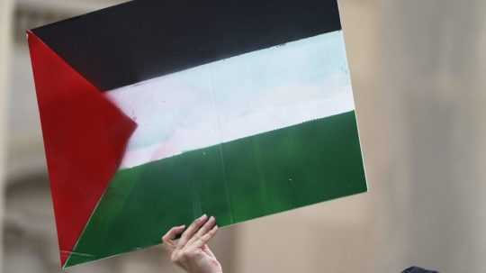 Demonštrantka drží palestínsku vlajku.