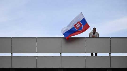 Muž drží slovenskú vlajku.