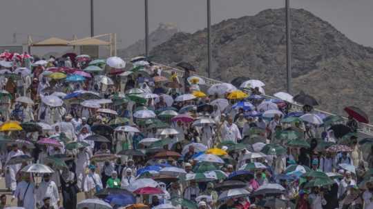 Moslimskí pútnici používajú dáždniky, aby sa chránili pred slnkom.