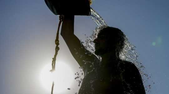 Muž si leje vodu na hlavu počas horúčav.